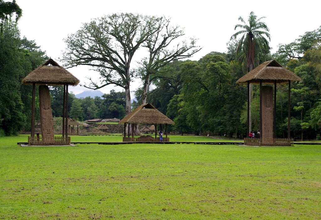 Looking across the Great Plaza. In the background you can see the Acropolis of Quirigua. In front you can see from left to the right: Stela E; Zoomorph G, Stela F